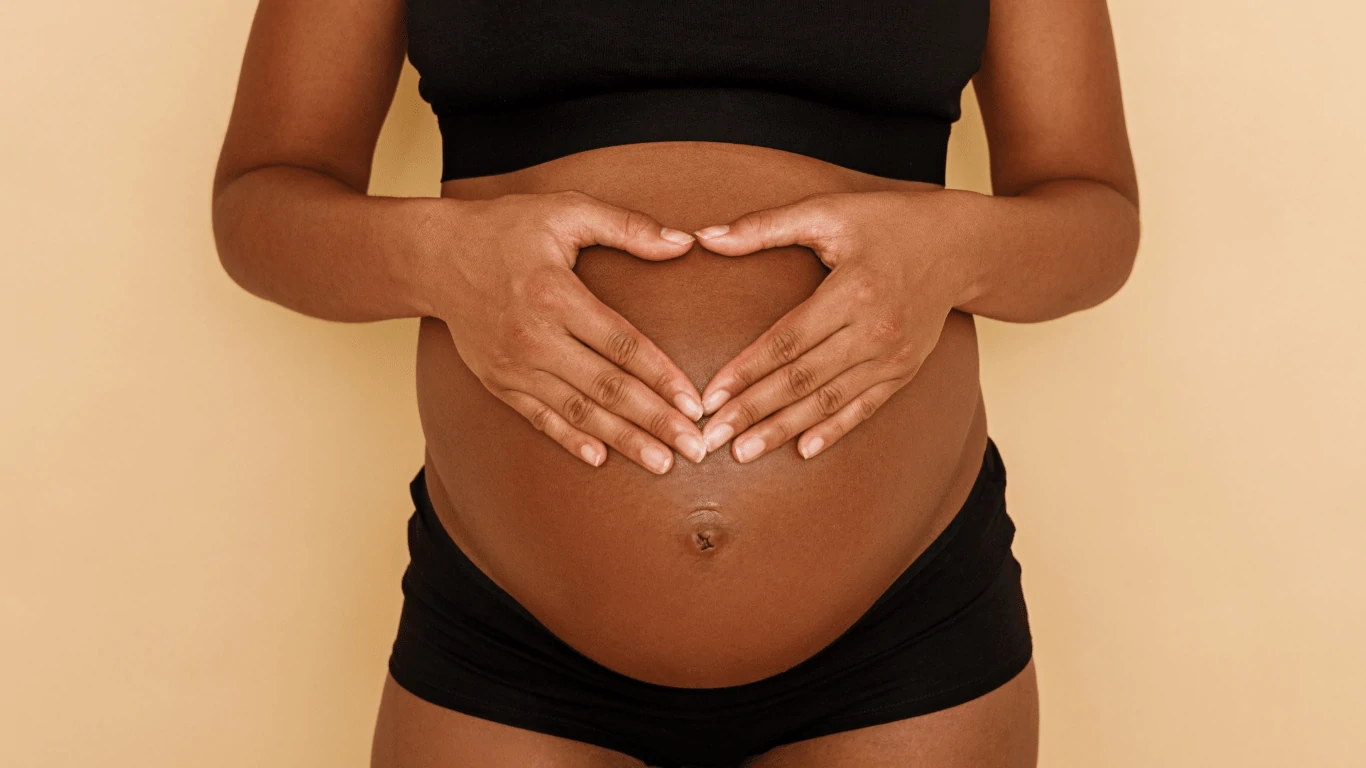 Pregnant woman holding her belly in heart shape